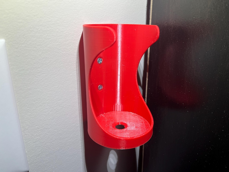 May include: A red plastic wall mount holder with two screws. The holder has a round opening at the bottom.