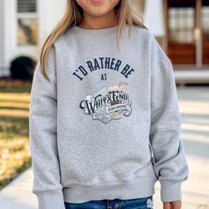 May include: A light gray sweatshirt with the text "I'd Rather Be at Whitts End Soda Shoppe" in navy blue and white. The graphic includes a soda with a straw. The sweatshirt is a casual style.