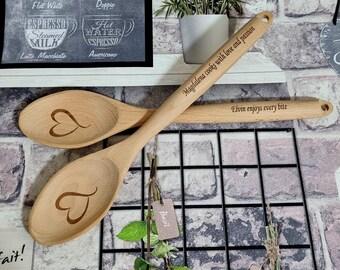 Puede incluir: Dos cucharas de madera con diseños de corazón grabados. Las cucharas están personalizadas con el texto "Magdalena cocina con amor y pasión" y "Elvin disfruta de cada bocado".