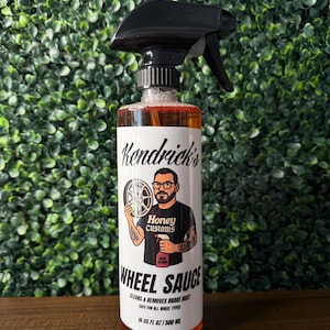 May include: A bottle of "Wheel Sauce" car cleaning product with a black spray nozzle. The label features a graphic of a man and a wheel. The bottle contains 500 ml of liquid and is designed to clean and remove brake dust.