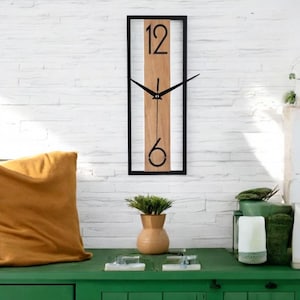 May include: A black framed clock with a wood panel and black numbers. The clock is hanging on a white brick wall.