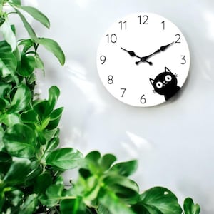 May include: A white round clock with black numbers and hands. A black cat with white eyes is peeking out from the right side of the clock.