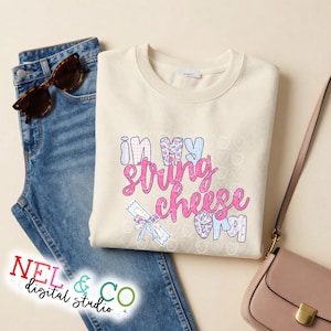 Könnte beinhalten: Cremefarbenes Sweatshirt mit dem Schriftzug "In My String Cheese Era" in einer farbenfrohen, verspielten Schriftart. Das Design umfasst florale und gemusterte Elemente. Das Sweatshirt wird mit blauen Jeans und Sonnenbrille gezeigt.