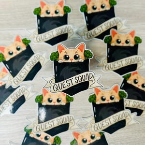 May include: Multiple stickers featuring a cartoon orange cat peeking out of a black pocket with the text "Quest Squad" on a white banner. The cat is surrounded by green broccoli.