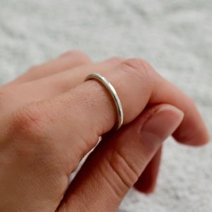 Könnte beinhalten: Ein dünner Silberring wird an einem Finger getragen. Der Ring hat ein schlichtes, minimalistisches Design und eine polierte Oberfläche. Der Ring besteht wahrscheinlich aus Sterlingsilber oder einem ähnlichen Metall. Der Ring ist ein Schmuckstück.