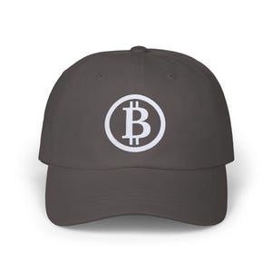 Puede incluir: Una gorra de béisbol gris oscuro con un logotipo de Bitcoin bordado en blanco.