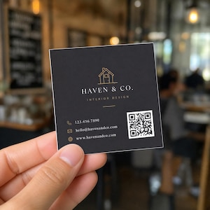 Hand holding a 2.5 inch square business card, showing the compact square format at true scale next to fingers.