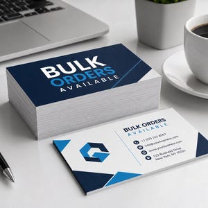 May include: A stack of business cards with the text "BULK ORDERS AVAILABLE" in white and blue. One card is displayed separately, showing a logo and contact information. A pen, laptop, and coffee cup are also in the image.
