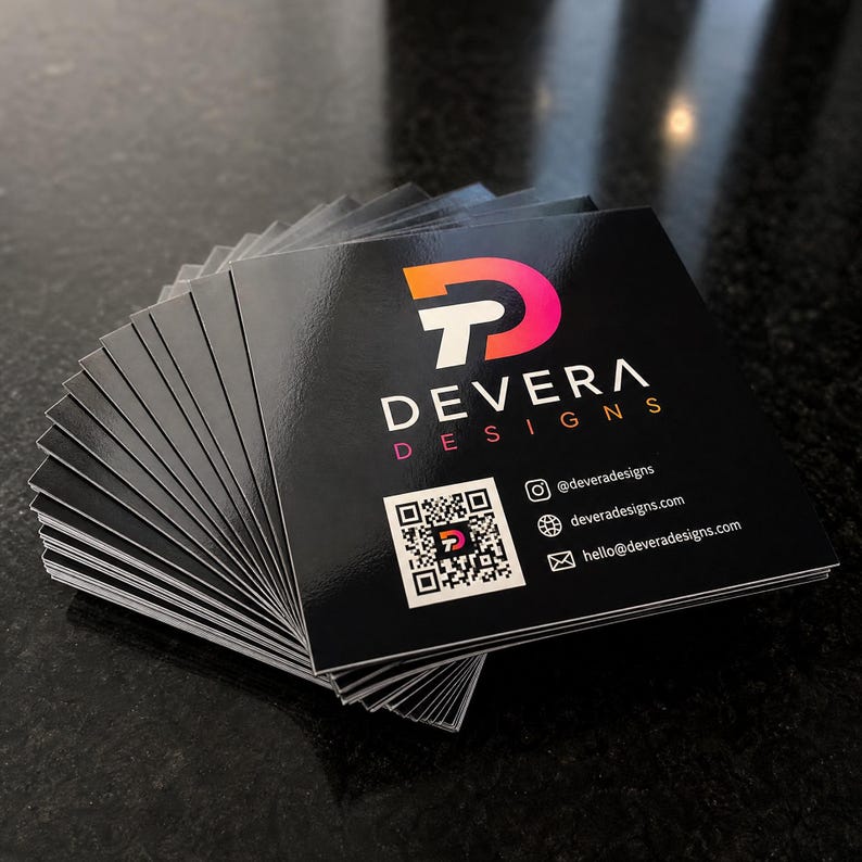 High gloss square business cards fanned in a stack, showing the reflective finish on thick black cardstock with a gradient logo and scannable QR code.