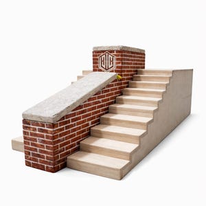 May include: A miniature architectural model featuring a brick wall with a concrete top, a ramp, and a set of wooden stairs. The brick structure has a logo on it. A small yellow flower is visible.