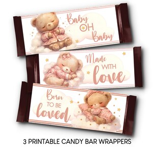 May include: Three printable candy bar wrappers with a baby shower theme. Each wrapper features a sleeping teddy bear on a cloud, with text that reads "Baby Oh Baby", "Made with Love", and "Born to be Loved".