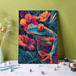 May include: A rectangular canvas print featuring a vibrant, colorful illustration of a red-eyed tree frog surrounded by large, bright orange and pink tropical hibiscus flowers and deep green foliage, set against a solid light green background.