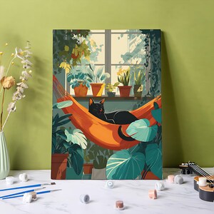 Puede incluir: Impresión en lienzo que representa un gato negro descansando en una hamaca naranja. El gato está frente a una ventana con plantas en macetas. La obra de arte tiene una combinación de colores verde y naranja, con un enfoque en plantas de interior y un ambiente acogedor.