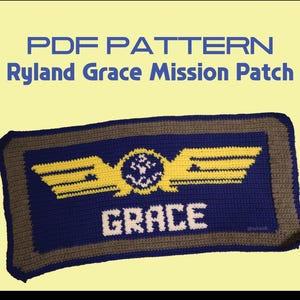 May include: A rectangular crochet patch featuring the text PDF PATTERN Ryland Grace Mission Patch. The patch has a blue centre with a yellow winged emblem, a circular detail, and the white text GRACE. It is bordered by a brown and dark blue frame.