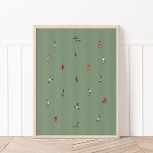May include: A framed art print featuring a soccer game illustration. The artwork depicts numerous small figures in various colored uniforms on a green field with vertical stripes. The players are engaged in action, suggesting a dynamic sports scene.