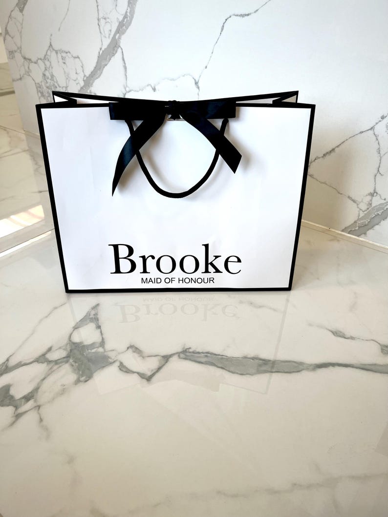 Personalised white gift bag featuring a custom name and decorative ribbon, great for bridal party presents