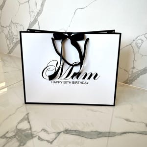 White luxury gift bag with rope handles, ribbon bow, and custom engraving for weddings, birthdays, or special occasions.
