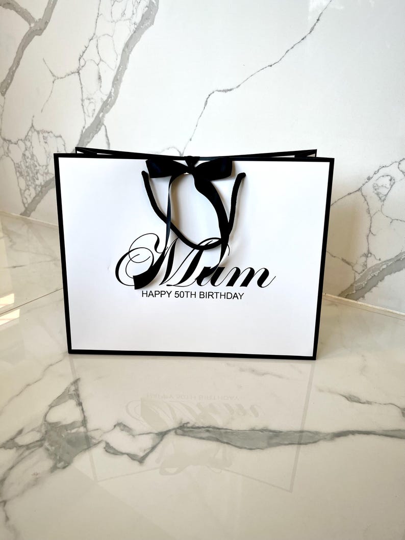 White luxury gift bag with rope handles, ribbon bow, and custom engraving for weddings, birthdays, or special occasions.