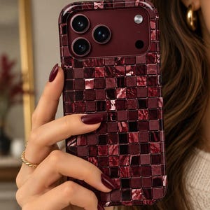 May include: A smartphone case featuring a dark burgundy and maroon mosaic tile pattern with a glossy finish. The design consists of small, square-shaped segments in varying shades of deep red, creating a textured appearance around the camera lens.