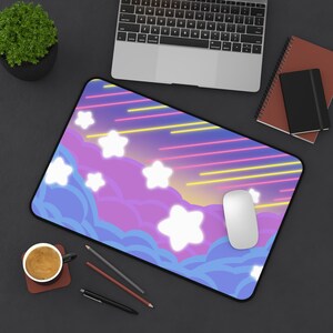 May include: A rectangular desk mat featuring a vibrant graphic design of white stars against a purple and blue cloud background with diagonal yellow and pink light streaks. The mat has a black border and a smooth surface for computer mouse use.