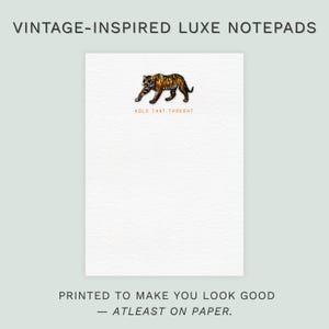 May include: White notepad with a detailed illustration of a tiger. The notepad has the text "HOLD THAT THOUGHT" and "PRINTED TO MAKE YOU LOOK GOOD - ATLEAST ON PAPER." The notepad is labeled "VINTAGE-INSPIRED LUXE NOTEPADS."