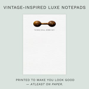 Puede incluir: Un bloc de notas blanco con una superficie texturizada, con una ilustración de mancuernas y el texto "THINGS WILL WORK OUT". El bloc de notas está etiquetado como "VINTAGE-INSPIRED LUXE NOTEPADS" y "PRINTED TO MAKE YOU LOOK GOOD - ATLEAST ON PAPER".