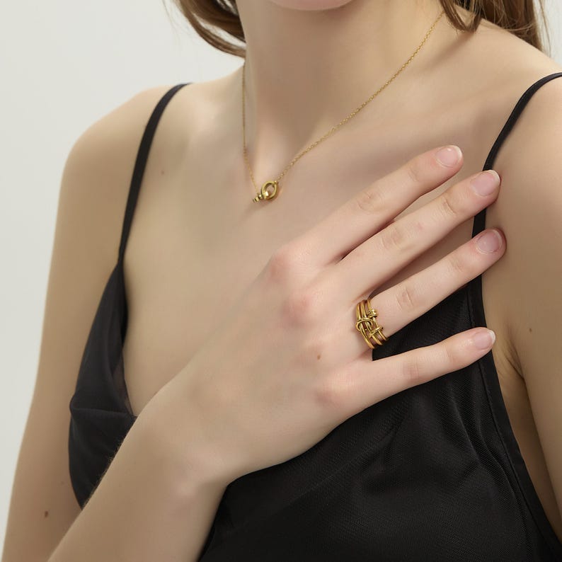 May include: Gold ring with a twisted design. The ring is worn on a finger.