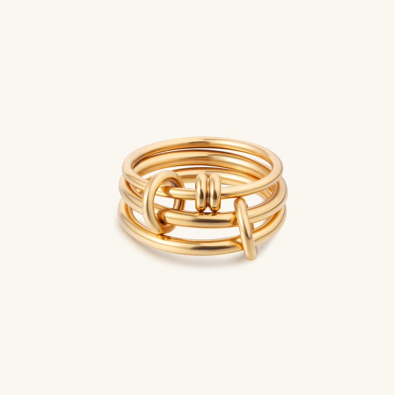 May include: Gold ring with a knotted design. The ring is made of four bands of metal that are intertwined.