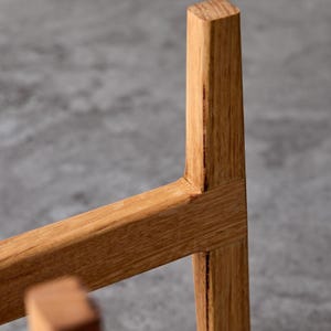 May include: Close-up of a wooden plant stand with a natural finish. The stand is made of solid wood and has a simple, modern design.