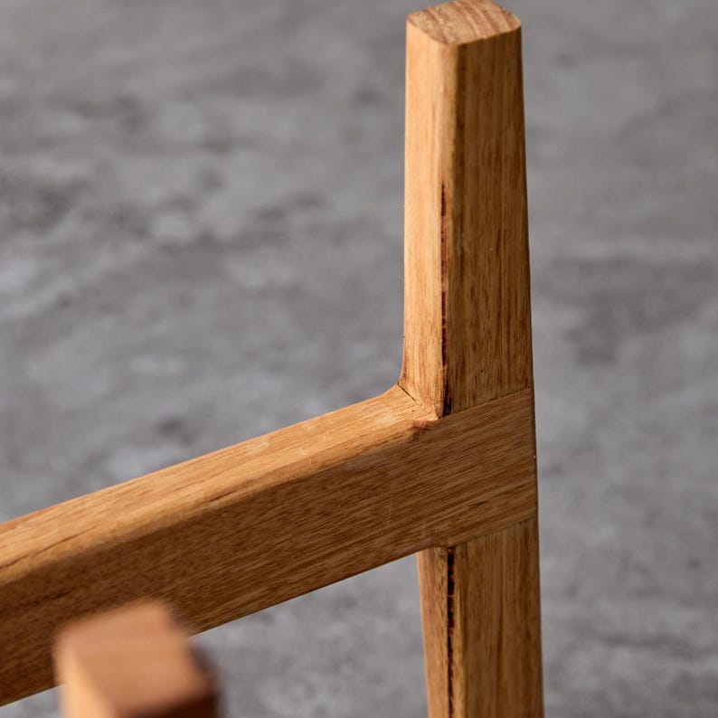 May include: Close-up of a wooden plant stand with a natural finish. The stand is made of solid wood and has a simple, modern design.