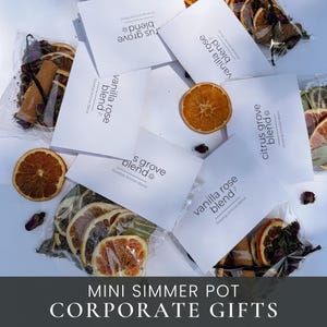 May include: Several clear plastic pouches containing dried orange slices, cinnamon sticks, and rosebuds, each with a white label reading citrus grove blend or vanilla rose blend, arranged with loose dried orange slices on a white surface.