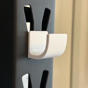 May include: White plastic hook attached to a black metal shelf unit.