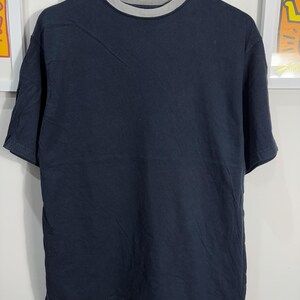 Peut inclure: Un t-shirt bleu foncé avec un col côtelé gris.