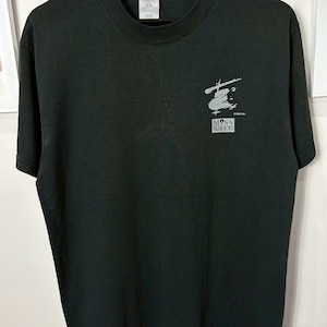以下が含まれることがあります： 黒いクルーネックTシャツ。前面には「Moss Saigon」の文字を含むグレーのグラフィックがあります。柔らかい素材で作られており、カジュアルウェアに適しています。