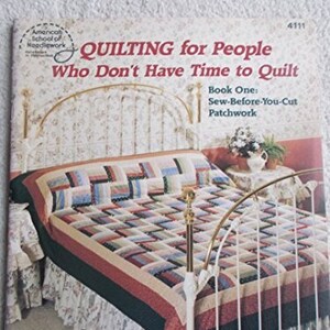 May include: A book titled "Quilting for People Who Don't Have Time to Quilt" by Marti Michell. The book cover features a photo of a bed with a patchwork quilt in shades of red, green, and white.