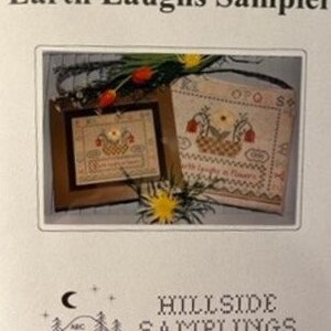 May include: A sampler cross stitch pattern titled "Earth Laughs Sampler" with two designs. The first design is a small, framed sampler with a basket of flowers and the text "Earth Laughs in Flowers". The second design is a larger sampler with a basket of flowers and the text "OPQRS".