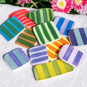 Peut inclure: Une collection de petites tuiles en c&eacute;ramique plates, rectangulaires et carr&eacute;es, orn&eacute;es de rayures verticales peintes &agrave; la main dans diverses couleurs comme le rouge, le vert, le bleu, l'orange, le jaune et le violet, avec une finition brillante.