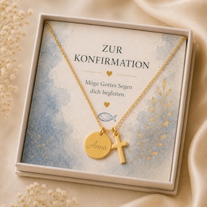 Könnte beinhalten: Eine goldfarbene Halskette mit einem runden Anhänger, der den Namen Anna trägt, und einem Kreuzanhänger. Die Kette liegt in einer weißen Geschenkbox mit einer Karte, auf der ZUR KONFIRMATION, Möge Gottes Segen dich begleiten steht.