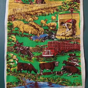 May include: A colorful tea towel with a rural scene. The towel features a green tractor, a red truck, sheep, cows, and a building with the text "Greetings from Temora NSW".