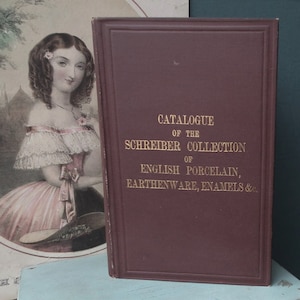 May include: A burgundy book titled "Catalogue of the Schreiber Collection of English Porcelain, Earthenware, Enamels &c."