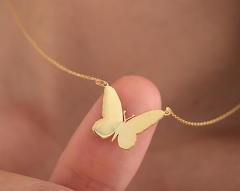 May include: A gold butterfly necklace with a delicate chain. The butterfly pendant is a simple silhouette design.