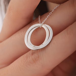 May include: Silver necklace with two interlocking circles, the smaller circle engraved with the word "Majoo".