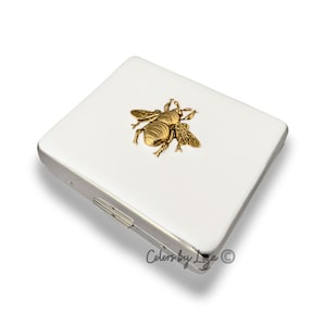 Il portapillole settimanale Gold Bee ha 8 scomparti intarsiati in smalto bianco dipinto a mano ispirato all'Art Nouveau. Opzioni di colore personalizzate e personalizzabili.
