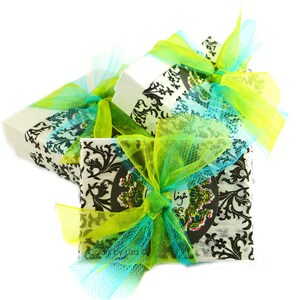 Puede incluir: Tres cajas de regalo envueltas en papel blanco con dise&ntilde;os en blanco y negro. Las cajas est&aacute;n atadas con cintas y lazos verdes y azules.
