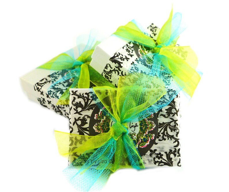Puede incluir: Tres cajas de regalo envueltas en papel blanco con dise&ntilde;os en blanco y negro. Las cajas est&aacute;n atadas con cintas y lazos verdes y azules.