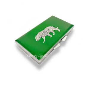 May include: A green metal card holder with a silver tiger design. The card holder has a hinged closure.