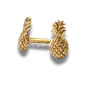Op de afbeelding: Een paar gouden ananas oorbellen. De oorbellen zijn gemaakt van metaal en hebben een gedetailleerd ananas ontwerp.