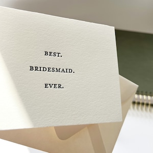 May include: A white card with black text that reads "BEST. BRIDESMAID. EVER."