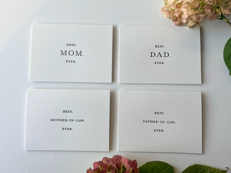 May include: Four white cards with black text. The cards read "Best. Mom. Ever.", "Best. Dad. Ever.", "Best. Mother-in-Law. Ever.", and "Best. Father-in-Law. Ever."