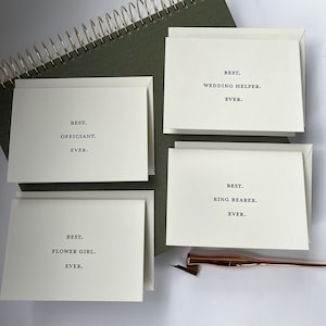 May include: Four white cards with black text. The cards read "Best. Officiant. Ever.", "Best. Flower Girl. Ever.", "Best. Wedding Helper. Ever.", and "Best. Ring Bearer. Ever."